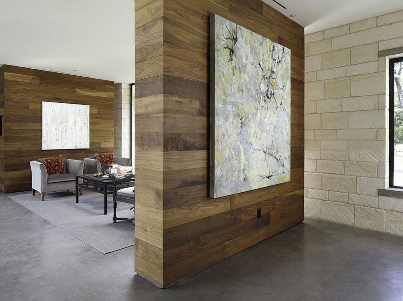 Vách ngăn phòng  bằng bê tông được ốp gỗ dán bên ngoài, kết hợp tranh treo tường đặc sắc, cho không gian khách thêm phần ấn tượng